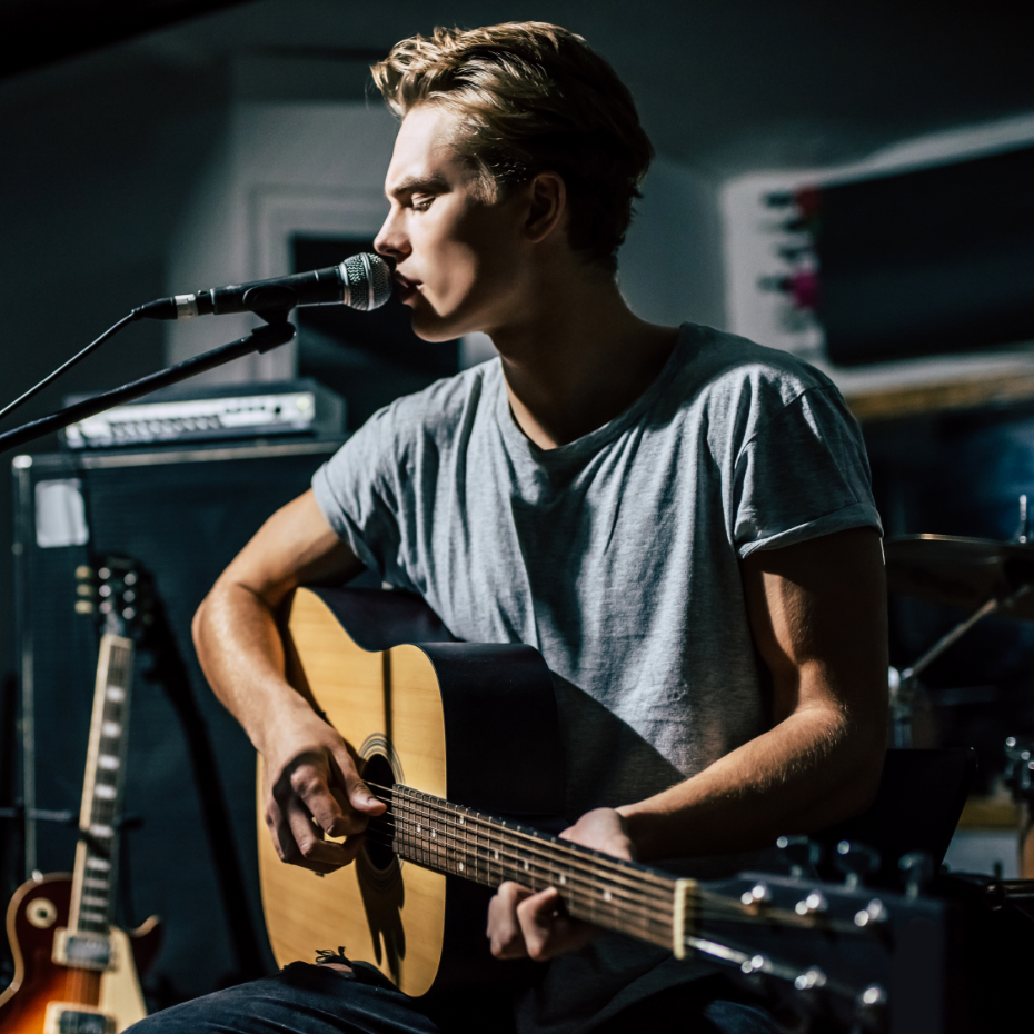 Sänger mit GItarre am Mikrofon.